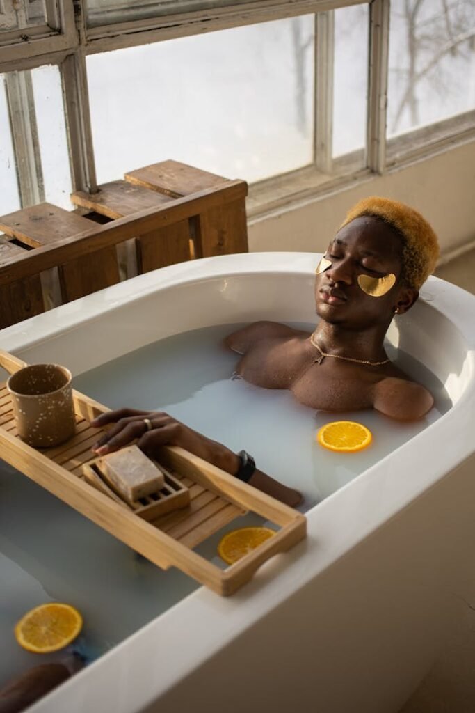 Black man with eye patches lying in bath during spa procedure